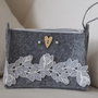 Astuccio in FELTRO. Grigio chiaro. Pochette porta trucco,porta penne,piccoli oggetti. Con cerniera .Applicato un nastro vintage,svizzero,fiori  in tulle ,due perle ed un cuore in legno.Fatta a mano