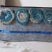 Astuccio portatrucco,penne, in feltro grigio chiaro.Applicate 4 rose tubolari (lana-cotone) gradazione beige-turchese-blu e paillettes blu