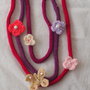 COLLANA in maglia di lana(tricotin) 3 fili.Applicazione di 4 fiori uncinetto e 1 farfalla.Strass,perline,perle.Toni del viola.Diversi colori