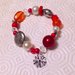 Braccialetto con perle e perline elastico nelle tonalità del rosso, bianco e argento con ciondolino a fiore, fatto a mano 