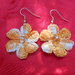 Orecchino a forma di fiore, con sei petali ed una perlina centrale, realizzato con filo di cotone color arancio.