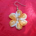 Orecchino a forma di fiore, con sei petali ed una perlina centrale, realizzato con filo di cotone color arancio.
