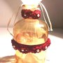 Bottiglietta in vetro fumè color ambra decorata a mano con roselline rosso scuo assemblate e cucite su un nastro in tulle con una piccola perla al centro di ognuna