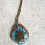 Collana con pendente in legno, vetro, cordoncino azzurro, sassolini e conchigliette.