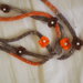 Collana in maglia tubolare.3 FILI.(lana-seta-cotone)Screziata:beige /marrone/arancione.9 Fiori a crochet con perle centrali.Accessorio di charme