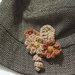 Spilla decorativa per cappello,borsa,giacca.Fiori di lana a telaio,foglie e riccioli all'uncinetto.Aggiunta di perline