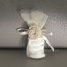 Sacchetto in tulle beige con  fiori in rilievo chiusi con un nastro in raso e fiore-bottone realizzato in cordoncino 