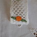 Bracciale di cotone bianco,in pizzo all'uncinetto.Applicazione di fiori e foglie a contrasto (arancione),chiuso da un bottone.Indurito per facilitare il modo di indossarlo.A richiesta varianti.