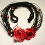 Collana realizzata a mano in cordone cerato nero con fiori rossi all’uncinetto e perline indiane e perle di plastica.