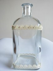 Bottiglietta in vetro decorata con bordini in pizzo di cotone avorio