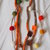 Collana in maglia tubolare.2 fili scalari(lana-seta-cotone)4 fiori a crochet(arancio-marrone).Bottoni a cuore (legno)Filo di palline in feltro in tinta