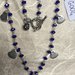 Collana girocollo con perline di agata blu e ciondoli in metallo a forma di cuore.