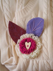 SPILLA in lana e feltro.Due fiori sovrapposti lavorati a telaio,foglie in feltro ricamate.Bottone a cuore in legno.Fuchsia,ciclamino e lilla.