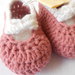 Scarpine crochet ballerine in lana rosa, con fiocco bianco.