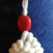 Ciondolo tessile conchiglione bianco in cotone realizzato ad uncinetto con punto molto decorativo ed impreziosito con corallo rosso in ceramica