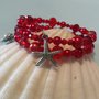 Bracciale con perline e cristalli nei toni del rosso con charms granchio e stella marina