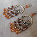 Orecchini chandelier con cristalli dorati di varie gradazione e motivo in metallo a forma di fiore.